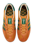 Pair of orange Adidas sneakers with green accents on a white background